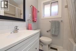 Bathroom featuring a white vanity with integrated sink, chrome faucet, and subway tile backsplash - 