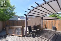 Expansive wood-finish deck featuring a covered pergola with retractable shade panels, and privacy curtains - 