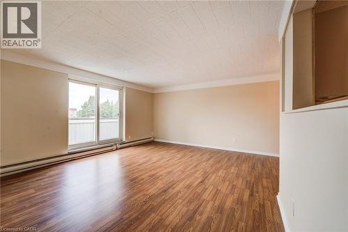Spacious living area featuring wood-finish flooring, neutral wall tones, and crown molding - 75 Hazelglen Drive Unit# 310, Kitchener, ON 