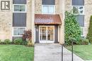 Building entrance featuring a brick facade, glass entry doors, and a corrugated metal awning - 75 Hazelglen Drive Unit# 310, Kitchener, ON 