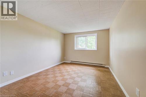 Room featuring checkered wood-finish flooring, light beige walls, and a white window frame - 75 Hazelglen Drive Unit# 310, Kitchener, ON 