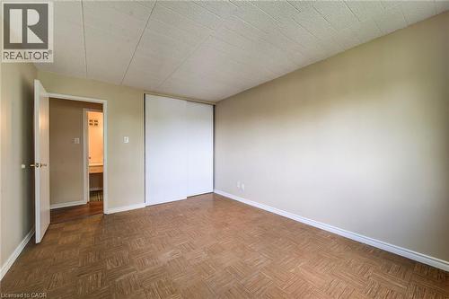 Spacious interior room with wood-finish parquet flooring, light-toned walls, and white trim - 75 Hazelglen Drive Unit# 310, Kitchener, ON 
