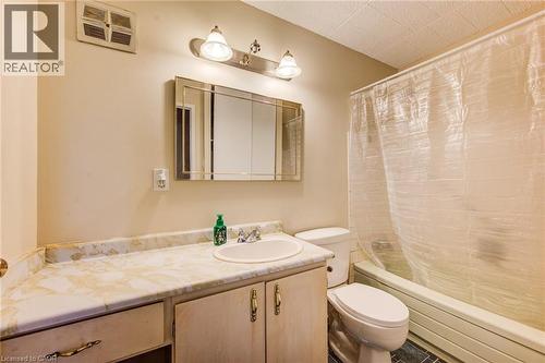 Bathroom featuring a vanity with a laminate countertop, integrated sink, and wood-finish cabinetry - 75 Hazelglen Drive Unit# 310, Kitchener, ON 