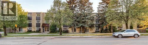 Three-story apartment building featuring a brick and panel facade, multiple windows, and a covered entryway - 75 Hazelglen Drive Unit# 310, Kitchener, ON 