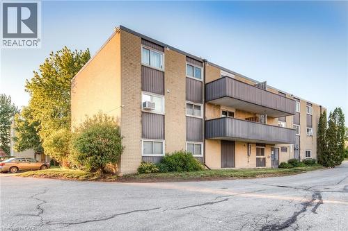 Multi-story residential building featuring light brick veneer and dark paneling accents - 75 Hazelglen Drive Unit# 310, Kitchener, ON 