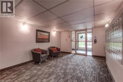 Entryway featuring patterned carpet flooring, ceiling-mounted lighting, and a wall of individual mailboxes - 75 Hazelglen Drive Unit# 310, Kitchener, ON 