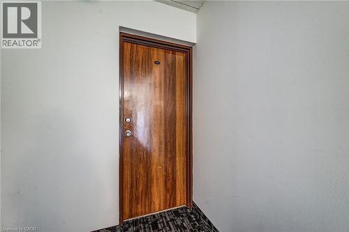 Entry door featuring a rich wood-finish panel, dark wood-finish trim, and stainless steel hardware - 75 Hazelglen Drive Unit# 310, Kitchener, ON 