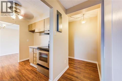 Kitchenette featuring wood-finish flooring, light cabinetry, and a stainless-steel range - 75 Hazelglen Drive Unit# 310, Kitchener, ON 