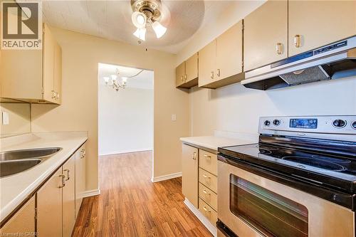 Kitchen featuring wood-finish flooring, light-toned cabinetry, a stainless steel range, and dual stainless steel sinks - 75 Hazelglen Drive Unit# 310, Kitchener, ON 