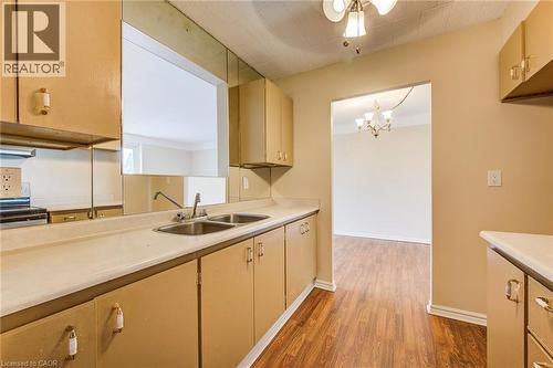 Kitchen featuring wood-finish flooring, dual basin stainless steel sink, and ample cabinetry - 75 Hazelglen Drive Unit# 310, Kitchener, ON 