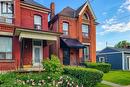 Brick exterior featuring architectural detailing, a covered front porch with wrought iron railing, and a gabled roofline - 244 Hughson Street N, Hamilton, ON 