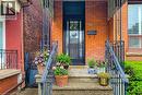 Brick facade entry with stone steps and wrought iron railings, featuring a black front door with glass panels and a transom window - 244 Hughson Street N, Hamilton, ON 