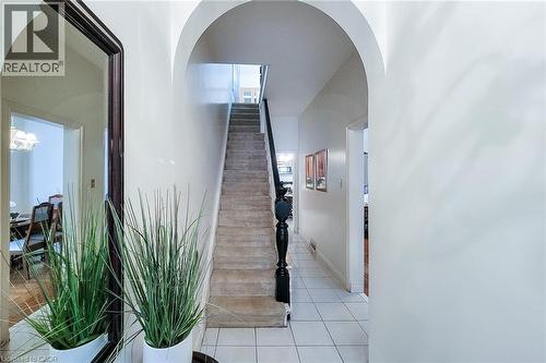 Archway entry hallway featuring white tile flooring and a carpeted staircase with a dark wood baluster - 244 Hughson Street N, Hamilton, ON 
