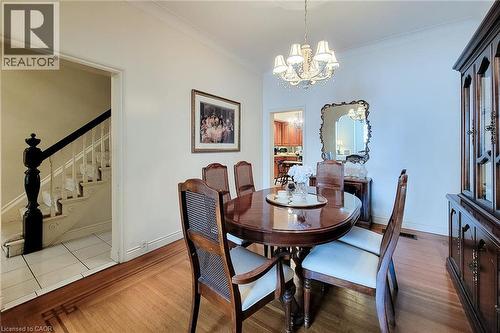 Dining space featuring wood-finish flooring with intricate inlay, crown molding, and a chandelier with decorative shades - 244 Hughson Street N, Hamilton, ON 