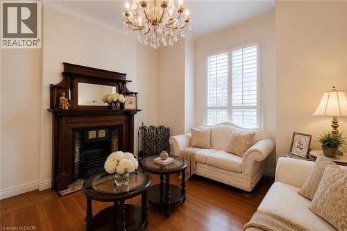 Living area featuring a detailed wood-finish fireplace surround with an integrated mirror, decorative tile insert, and a cast iron fireback - 244 Hughson Street N, Hamilton, ON 