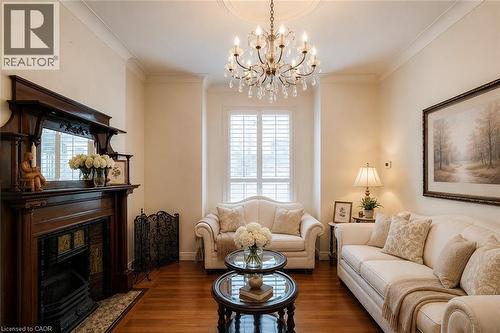 Formal living area featuring wood-finish flooring, an ornate chandelier with crystal accents, and crown molding - 244 Hughson Street N, Hamilton, ON 
