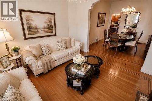 Living area featuring wood-finish flooring with intricate inlay, an arched entryway, and neutral wall tones - 244 Hughson Street N, Hamilton, ON 