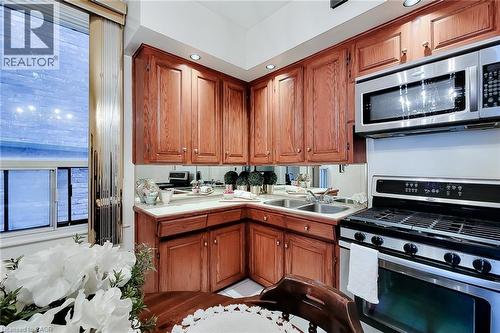 Kitchen featuring wood-finish cabinetry, stainless steel appliances, a double basin sink, and recessed lighting - 244 Hughson Street N, Hamilton, ON 