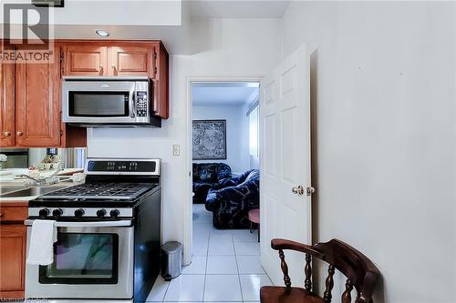Kitchen featuring wood-finish cabinetry, stainless steel microwave, and stainless steel range - 244 Hughson Street N, Hamilton, ON 