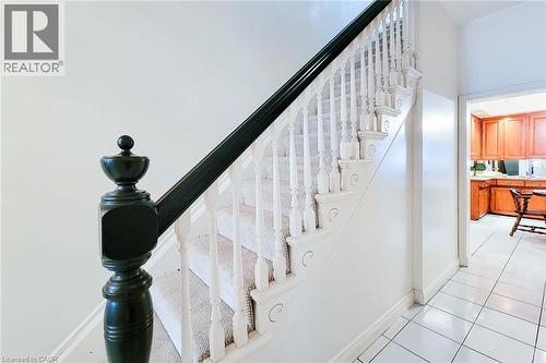 Staircase featuring a dark newel post and handrail, white balusters, and carpeted treads - 244 Hughson Street N, Hamilton, ON 