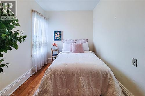 Hardwood flooring with prominent baseboards, light-colored walls, and a window with sheer curtains - 244 Hughson Street N, Hamilton, ON 