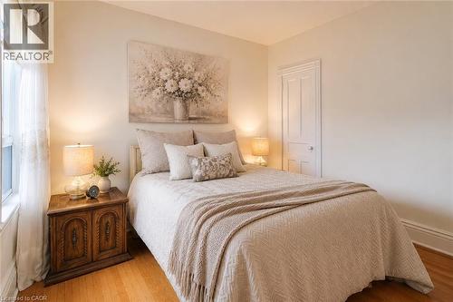 Bedroom featuring wood-finish flooring, a white paneled door, and a single window with white trim - 244 Hughson Street N, Hamilton, ON 