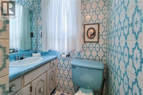 Bathroom featuring full-height patterned wall tiling and a coordinating blue toilet and countertop - 244 Hughson Street N, Hamilton, ON 