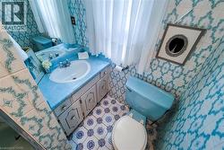 Bathroom featuring patterned blue and white wall tiles, blue vanity countertop, white sink, white window sheers, and blue toilet - 