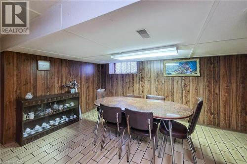 Finished room featuring wood-panel walls and light-toned tile flooring - 244 Hughson Street N, Hamilton, ON 
