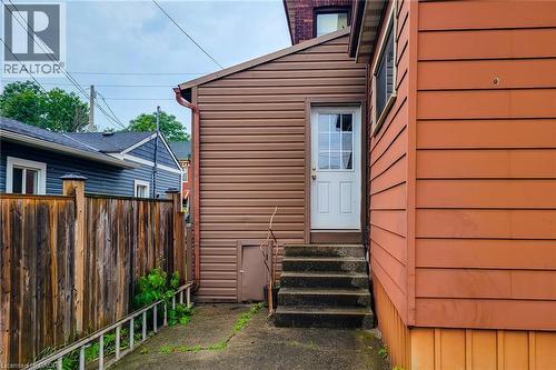 Exterior access featuring a white paneled door with windowpanes, concrete steps, and a privacy fence - 244 Hughson Street N, Hamilton, ON 