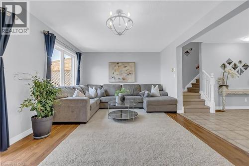 Spacious living area featuring wood-finish flooring, a large area rug, and a contemporary chandelier - 48 Clough Crescent, Guelph, ON 