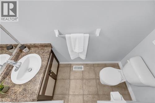 Bathroom featuring a brown vanity with an integrated sink, polished chrome faucet, and a large wall-mounted mirror - 48 Clough Crescent, Guelph, ON 