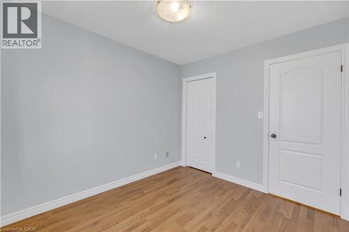 Room featuring wood-finish flooring, light grey painted walls, white trim, and a semi-flush mount ceiling light - 48 Clough Crescent, Guelph, ON 