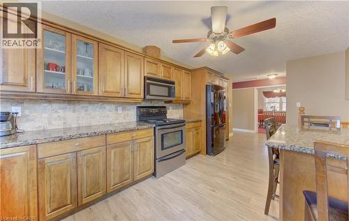 Kitchen featuring wood-finish cabinetry, stainless steel appliances, granite countertops, and a tiled backsplash - 599 Coldstream Drive, Waterloo, ON 