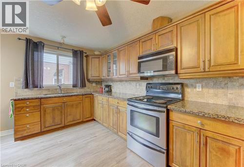 Kitchen featuring wood cabinetry, light-colored countertops, stainless steel appliances, and wood-finish flooring - 599 Coldstream Drive, Waterloo, ON 