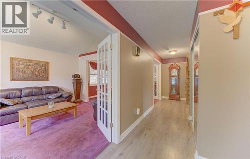 French doors opening to a living area with track lighting, a vaulted ceiling, and plush purple carpeting - 599 Coldstream Drive, Waterloo, ON 