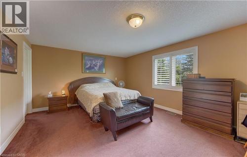 Carpeted room with a ceiling-mounted light fixture and a window featuring white plantation shutters - 599 Coldstream Drive, Waterloo, ON 