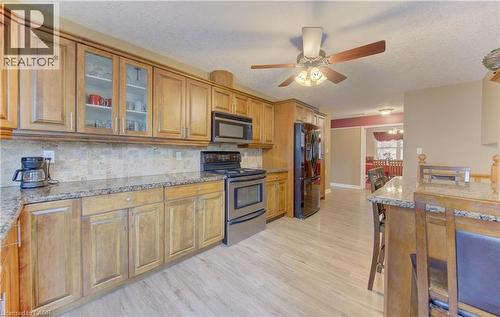Kitchen featuring wood cabinetry, granite countertops, and a tiled backsplash - 599 Coldstream Drive, Waterloo, ON 