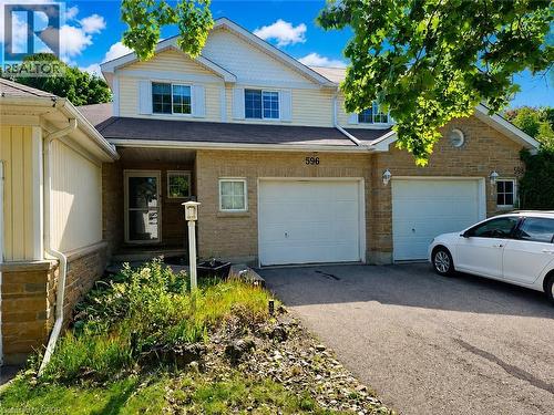 Brick and siding exterior featuring two single-car garages with white doors, a paved driveway, and multiple windows with white trim - 596 Spinnaker Crescent, Waterloo, ON 