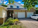 Brick and siding exterior featuring two single-car garages with white doors, a paved driveway, and multiple windows with white trim - 596 Spinnaker Crescent, Waterloo, ON 
