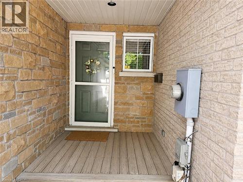 Covered entry featuring natural stone facade, composite decking, and a panel door with a screen door - 596 Spinnaker Crescent, Waterloo, ON 