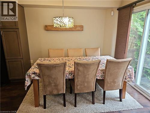 Dining area featuring a contemporary pendant light fixture, built-in cabinetry, and wood-finish flooring - 596 Spinnaker Crescent, Waterloo, ON 