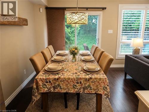 Open dining area featuring wood-finish flooring, a contemporary pendant light fixture, and a sliding glass door providing exterior access - 596 Spinnaker Crescent, Waterloo, ON 