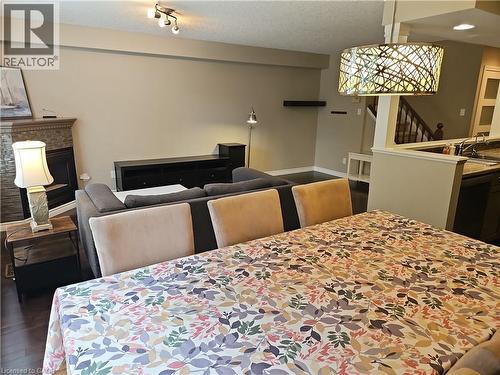 Open-concept living area featuring dark wood-finish flooring, a fireplace with a stone tile surround, and a decorative overhead light fixture - 596 Spinnaker Crescent, Waterloo, ON 