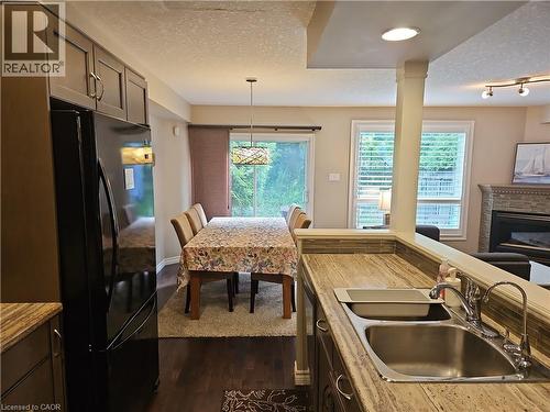 Kitchen with dark wood-finish cabinetry, stainless steel double-basin sink, and a contrasting stone-finish countertop - 596 Spinnaker Crescent, Waterloo, ON 
