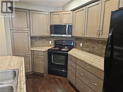 Kitchen featuring light-toned cabinetry, granite-patterned countertops, and dark wood-finish flooring - 596 Spinnaker Crescent, Waterloo, ON 