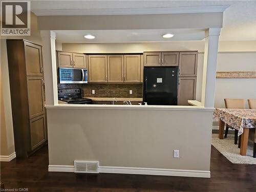 Kitchen featuring recessed lighting, a built-in microwave, dark wood-finish flooring, a tiled backsplash, and dark cabinetry - 596 Spinnaker Crescent, Waterloo, ON 