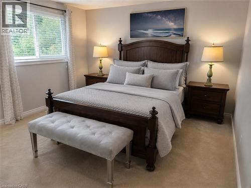 Spacious bedroom featuring neutral wall paint, light-toned carpeting, a large window with horizontal blinds, and a built-in ceiling light fixture - 596 Spinnaker Crescent, Waterloo, ON 