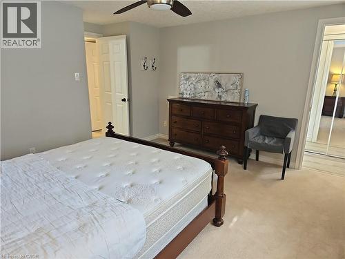 Bedroom featuring light gray walls, plush carpet flooring, a ceiling fan with integrated lighting, and a mirrored closet door - 596 Spinnaker Crescent, Waterloo, ON 
