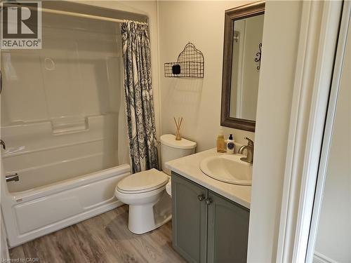 Bathroom featuring a fiberglass tub/shower combination, wood-finish flooring, and a vanity with a white countertop and a single basin sink - 596 Spinnaker Crescent, Waterloo, ON 